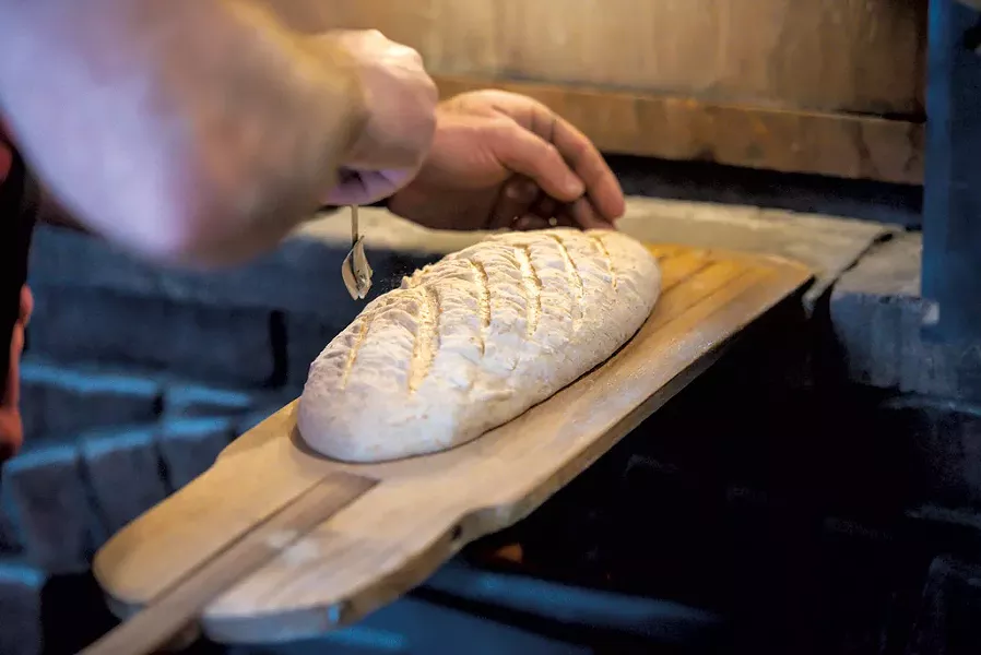 Scoring a sourdough bâtard before putting it in the oven - GLENN RUSSELL