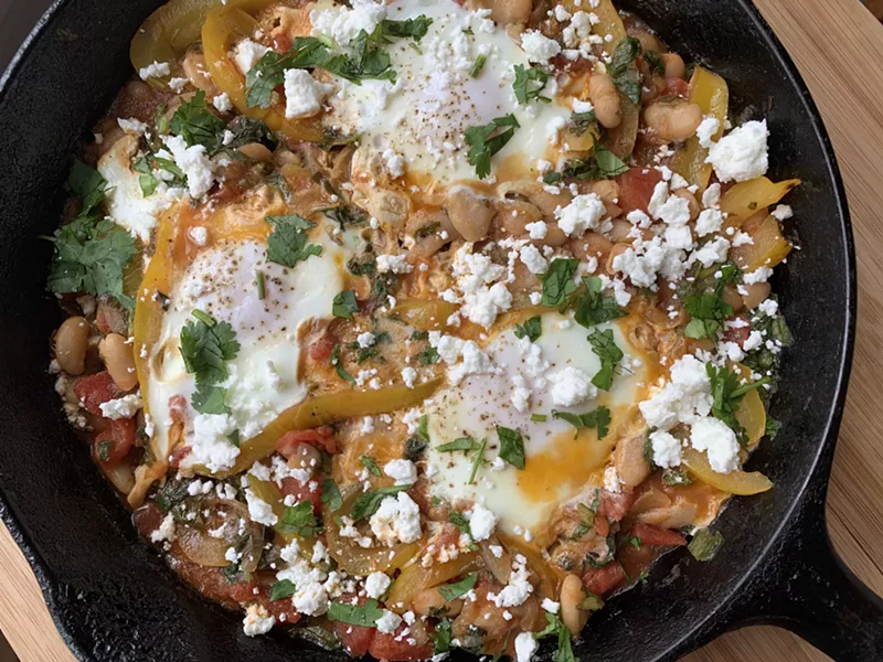 Shakshuka of tomatoes, yellow pepper and radish greens with poached eggs - MELISSA PASANEN