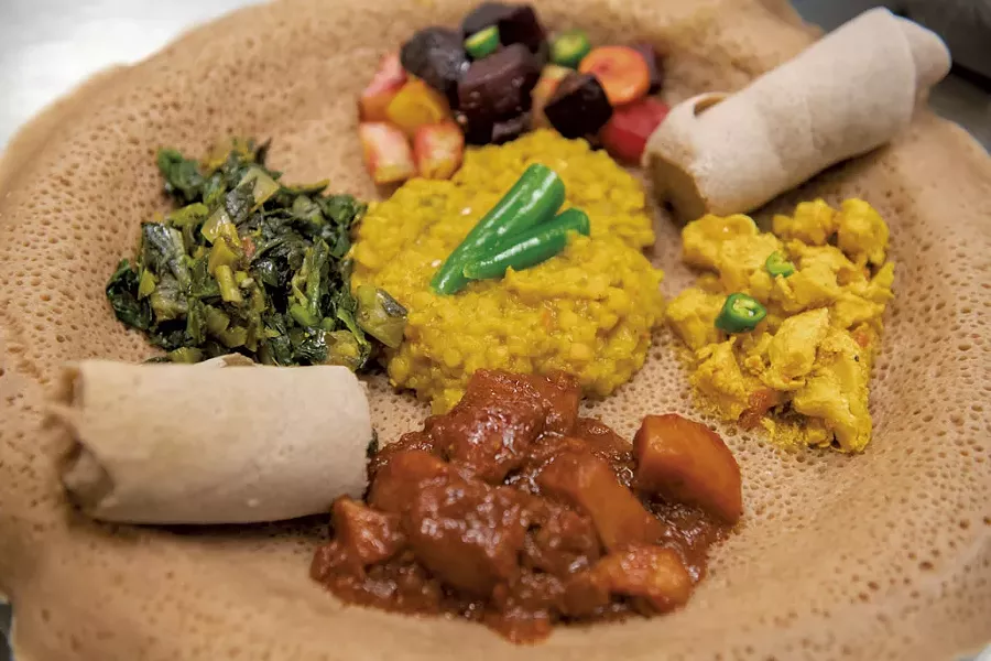 Ethiopian and Eritrean lentils, carrots, beets and potatoes, collard greens, curried chicken, and spicy potatoes, served on injera bread, for a takeout dinner at the O'Brien Community Center - DARIA BISHOP