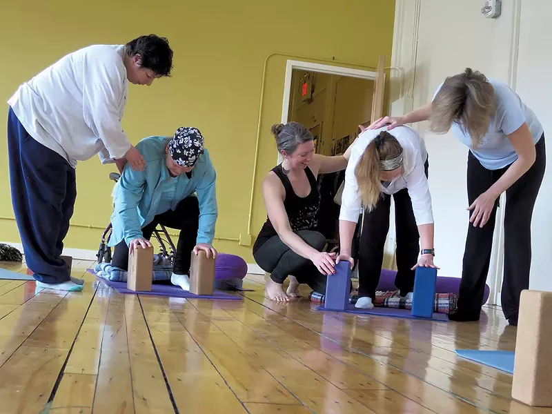 Teresa Wynne (black tank top) assisting yoga students - MATTHEW THORSEN