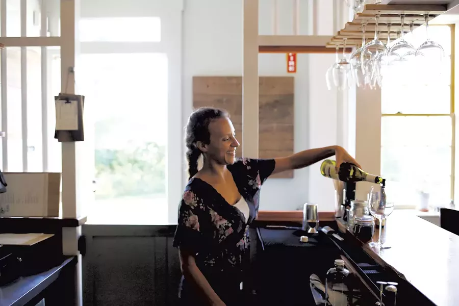 Jayne Sully Cole pouring a glass of wine at the vintage bar - SARAH PRIESTAP