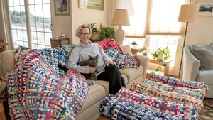 Julie Reville and her cat Cushie with some of her upcycled "potholder rugs"
