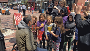 Newspaper staffers from George Leal's second grade class at the Integrated Arts Academy interviewing bystanders on Church Street after a flash mob featuring fellow students