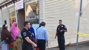 Officers and onlookers by the Namaste Community Center at Union Street and Malletts Bay Avenue