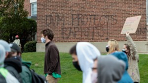 Students march past graffiti criticizing UVM in 2021