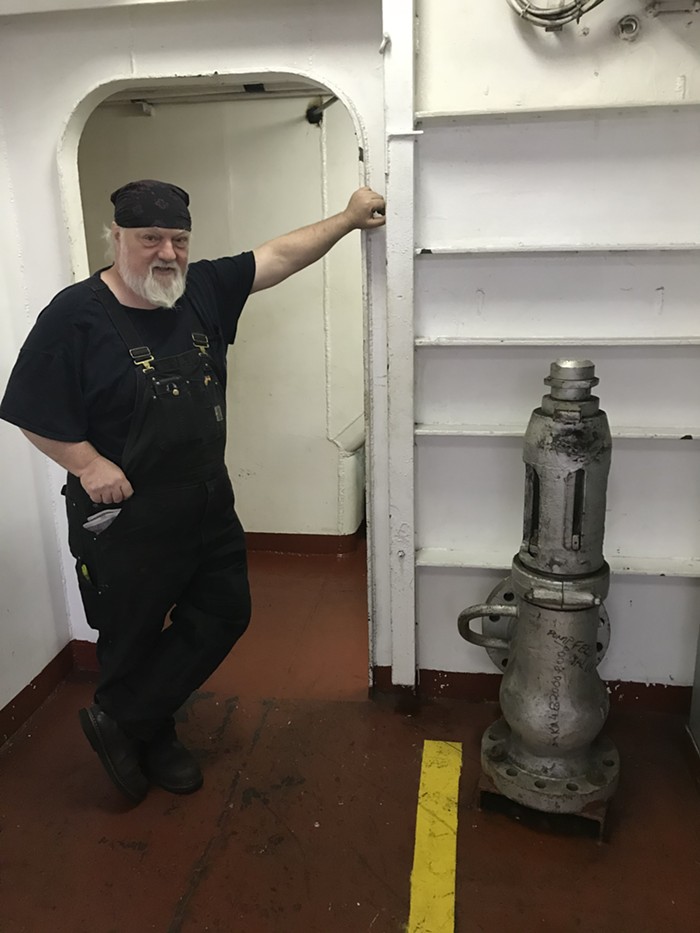 Thompson poses next to the ships pressure valve. He says the valve operates like the one on your pressure cooker at home.