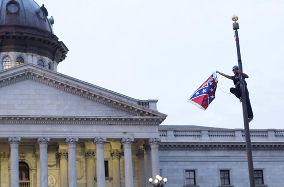 Activist Bree Newsome reaches her apex, taking down the Confederate battle flag at the South Carolina Statehouse on June 27. New Richmond resident Trevor FitzGibbon helped guide her group through the ensuing media blitz. - REUTERS/ADAM ANDERSON