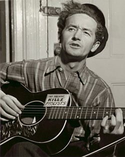 Woody Guthrie, Half Length Portrait, - Facing Slightly Left, Holding Guitar , - 1943 Al Aumuller (American active - 1930s early 1950s) gelatin silver - print . Prints and Photographs - Division, Library of Congress, - Washington D.C.