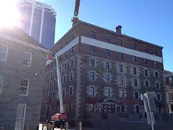 A single worker is painting over the historic Morse's Teas sign.