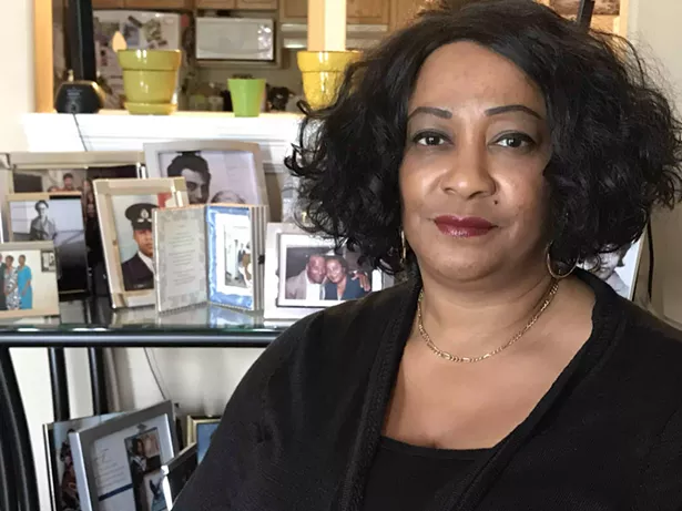 Marie Symonds sits in front of some of the family photos in her home. - THE COAST