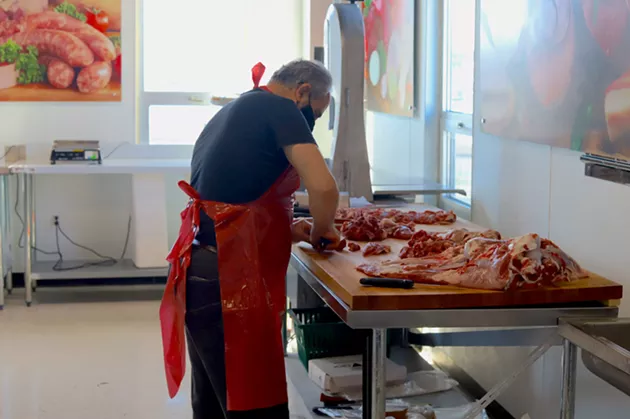 A butcher divides halal meat at Syriana Market the day before their grand opening. - VICTORIA WALTON