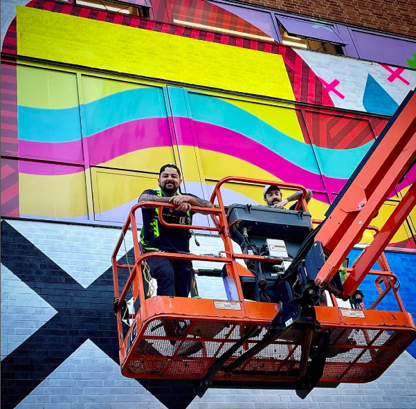 Jordan Bennett, left, with a project assistant, on site at his new OCAD mural, which will be unveiled June 15.
