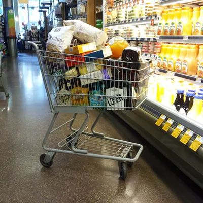 A filled shopping cart in a grocery aisle.