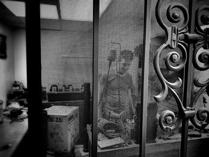 Patrick Carey at work behind the screen door of his tiny silversmithing and lapidary studio. - BRIAN SMITH