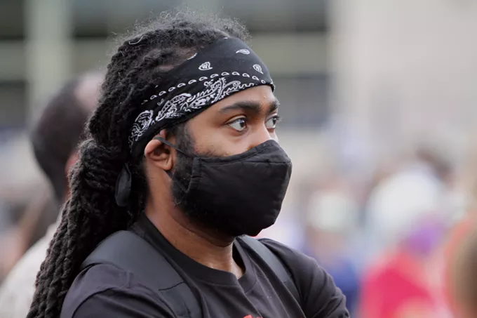 A person in the crowd listens to the testimony of Ashley Johnson, whose father was killed by an off-duty police officer after the officer racially profiled the 28 year-old-man while he was pumping gas. "I want our voices to be heard. I don't want our voices to be muted by all the rioting and looting," Johnson said. "I've been silent. I've been silent since I was a child. His trial was 15 years ago and that was the last time I spoke about it. He never got justice." - AUSTIN COUNTS