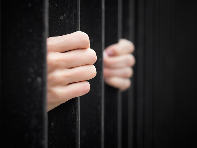 bigstock-prisoner-behind-jail-bars-73500814.jpg