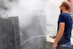 Distiller Nathan Thompson Avelino makes mesquite smoke to add character to the barley in the drying process. - HEATHER HOCH