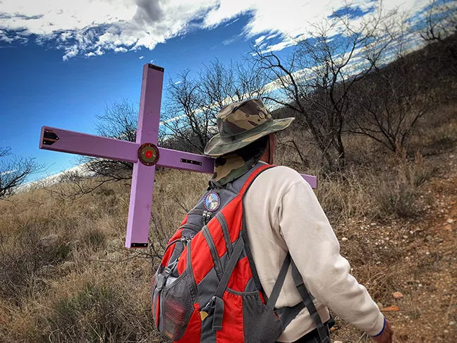Andre Rivera carries a cross to a death site. - PHOTOS BY BRIAN SMITH