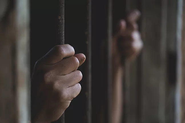 bigstock-man-in-prison-hands-of-behind--268838434.jpg